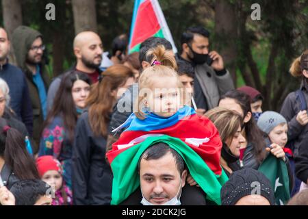 Ein Mädchen wickelte die aserbaidschanische Flagge auf die Schulter seines Vaters und sie feiern den Siegestag des Karabach-Krieges. Baku - Aserbaidschan: 10. November 2020. Stockfoto