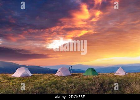 Vier Zelte auf einer herrlichen Wiese in den Sommerbergen. Touristenlager. Landschaftsfotografie, Reisekonzept Stockfoto