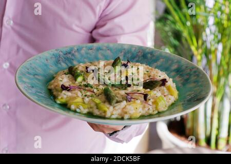 Ein Mann hält einen Teller Spargel Risotto, italienische Küche Stockfoto