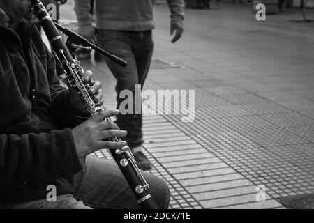 Hände eines jungen Mannes, der auf der Straße Klarinette spielt, als Fußgänger in La Serena, Chile, vorbeikommt. Straßenmusiker, Künstlerkonzept Stockfoto