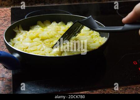 Traditionelle spanische Kartoffelomelette Kochen in Pfanne auf Glas Keramikkochfeld Stockfoto