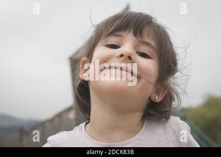 Nahaufnahme von lächelnden kleinen Mädchen mit Perle Ohrringe an parken Sie an bewölkten Tagen Stockfoto