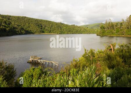 Cutipay Fluss mit kleinen zerbrochenen hölzernen Pier umgeben von Bergen in Valdivia, Südchile. Herrliche Natur grüne Landschaft Stockfoto