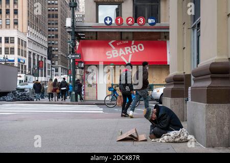 Manhattan, New York, USA. November 2020. Ein Obdachloser sitzt auf der Straße in der 7. Straße gegenüber von einem verschobelten SbarroÕs-Standort während der Covid-19-Pandemie in Manhattan, New York. Obligatorische Gutschrift: Kostas Lymperopoulos/CSM/Alamy Live News Stockfoto