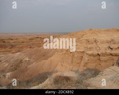 Gerillte, gerippte Berge mit bunten Hügeln im Hintergrund. Fotografiert bei Sonnenaufgang im Badlands National Park in South Dakota. Trübe oder rauchige Himmel ab Stockfoto