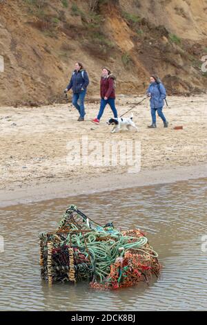 Verschmutzung. Verlorene Angelausrüstung. Überborder Hummertöpfe, farbiges Plastiknetz. Liegen im seichten Wasser am Happisburgh Strand. Hintergrund Ausübung Hund wal Stockfoto