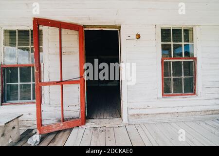 Alte rote Holztür wurde in einem verlassenen Gebäude aufgeklappt In Bannack Geisterstadt Montana Stockfoto