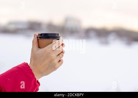 Eine junge Frau hält im Winter ein Glas heiß Kaffee oder Tee Stockfoto