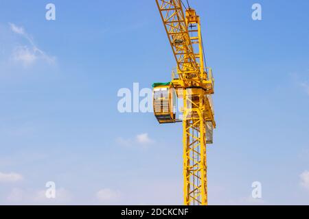 Gelber Kran wird beim Bau von hohen Gebäuden für Werkzeuge großer Industriezweige unter blauem Himmel und weißen Wolken verwendet. Stockfoto