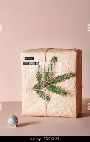 Weihnachts-Öko-Geschenkbox mit Text und Baumzweig auf beigem Hintergrund. Weihnachten keine Verschwendung. Platz kopieren Stockfoto