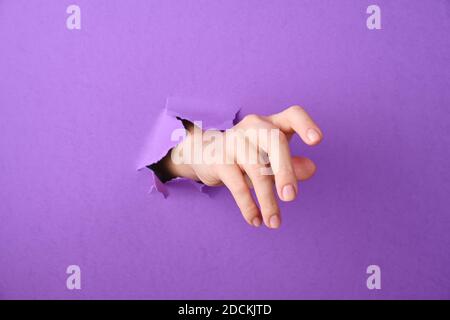 Die Hand wird durch ein Loch im Papierhintergrund geschoben Stockfoto