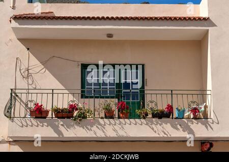 Balkon auf einem alten weiß getünchten Gebäude, dekoriert mit Blumen in Töpfen in der spanischen Stadt. Teneriffa, Spanien. Stockfoto