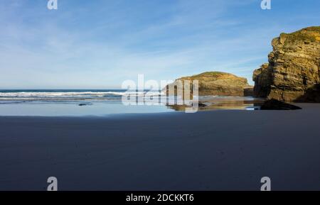 Ein warmer goldener Abend an einem Sandstrand mit zackigen Und schroffen Klippen Stockfoto