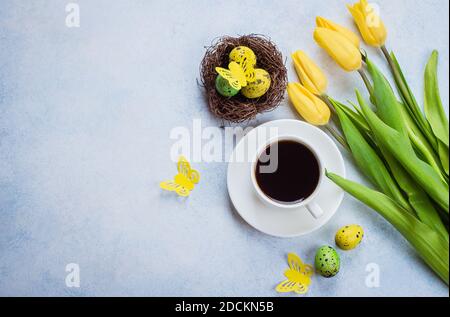 Gelbe Tulpen, Wachteleier und Tasse schwarzen Kaffee auf blauem Stein Hintergrund. Flach liegend, Draufsicht, Kopierbereich. Osterkonzept Für Frühlingsferien. Stockfoto