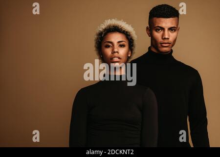 Paar auf braunem Hintergrund in schwarzer Kleidung. Porträt von afroamerikanischen Mann und Frau. Stockfoto