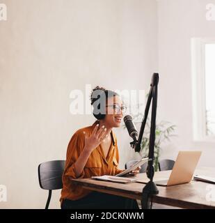 Professionelle weibliche Podcasterin macht einen Podcast aus dem Heimstudio. Frau, die von zu Hause aus einen Podcast aufzeichnet. Stockfoto