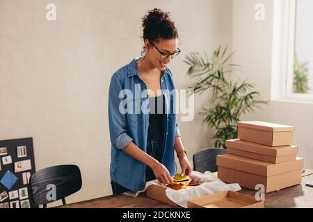 Kleine Unternehmer Verpackung hausgemachte Schutzmaske Gesicht in einer Box für den Versand an den Online-Client. Weibliche Unternehmerin, die auf Online-Masken oder Stockfoto