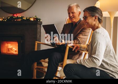 Ältere Männer und Frauen, die einen Videoanruf führen. Ältere Paare, die an Weihnachten ein digitales Tablet für Videoanrufe bei ihrer Familie verwenden. Stockfoto