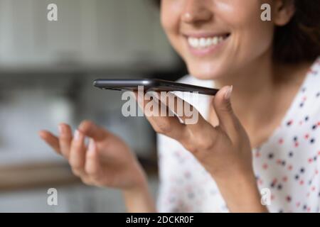 Lächelnde Frau zeichnet Sprachnachrichten auf dem Smartphone auf Stockfoto