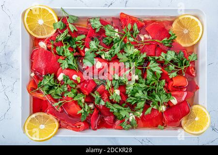 Rote Paprika, geröstet und geschält, mit Knoblauch, Öl und Petersilie. Bio marinierte geröstete rote Paprika in einer Schüssel. Stockfoto