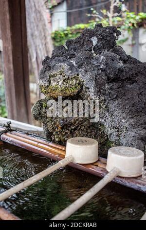 Ein natürliches steiniges Chozu Handwaschbecken bei einem Shinto Schrein in Japan Stockfoto