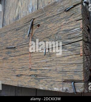 Ein altes, unbemaltes Holzbrett mit einigen Nägeln, die herausragen. Das Holz ist rau, verwittert und sieht alt aus. Es hat einige Risse. Holzstruktur Stockfoto