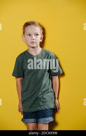 Porträt eines unfreundlichen zehnjährigen Jungen, der im Stehen steht Vorderseite der Wand Stockfoto