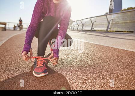 Vorbereitung. Eine kurze Aufnahme der aktiven reifen Frau, die Sportkleidung trägt und ihre Schnürsenkel bindet, während sie sich für das Laufen im Freien an einem sonnigen Tag vorbereitet Stockfoto