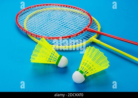 Zwei Federball- und Badminton-Schläger auf blauem Hintergrund. Aktive Erholung und Sport-Konzept. Leerzeichen für Text. Stockfoto