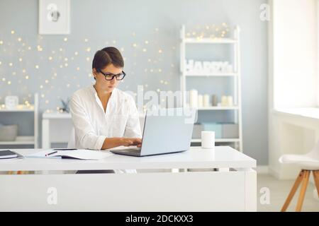 Geschäftsfrau in Brille sitzt zu Hause und arbeitet an Laptop online Stockfoto