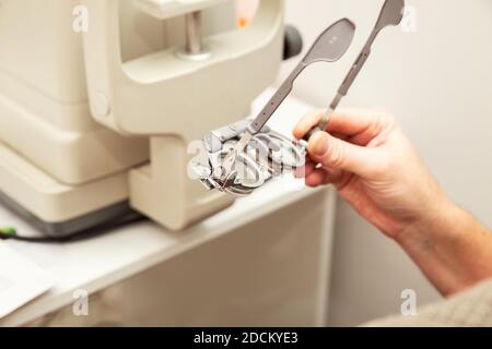 Die Hand des Mannes hält einen optometrischen Versuchsrahmen für die Dioptrieneinstellung. Augenklinik, Sehuntersuchung. Stockfoto