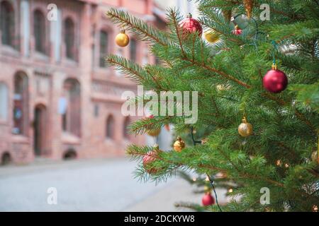 Nahaufnahme Details von echten geschmückten Weihnachtsbaum mit roten und goldenen Kugeln, leere Altstadt oder Stadt auf dem Hintergrund Stockfoto