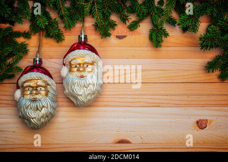 Weihnachten oder Neujahr Dekoration Hintergrund auf einem Holztisch mit Kopierraum und Draufsicht. Rahmendesign. Zwei hängende Weihnachtsmänner in Kiefernästen. Stockfoto