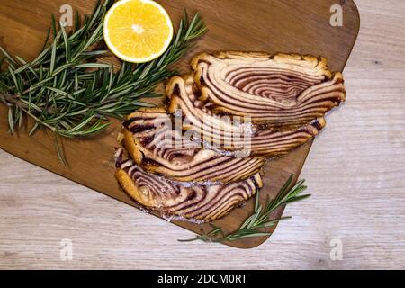 Süßes Dessert auf einem Holzbrett mit Gebäck in Scheiben serviert Roll und Zitrone halb mit Rosmarin Zweige verziert Stockfoto