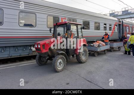 Der Traktor entfernt Müll aus einem Zug, der auf der Plattform steht Der sibirischen Stadt Barabinsk Bahnhof Stockfoto