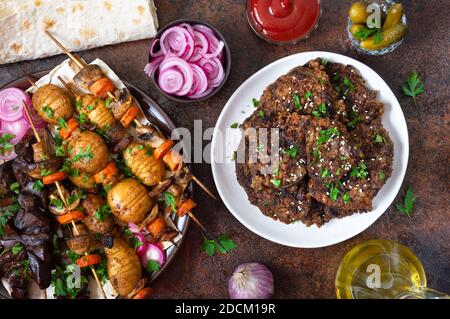 Verschiedene Gerichte Leberkebab. Spieße Leber, Vollgemüse und Pilze auf Spieße. Speisekarte vom Grill-Restaurant. Georgische, asiatische Küche. Flach liegend. Stockfoto