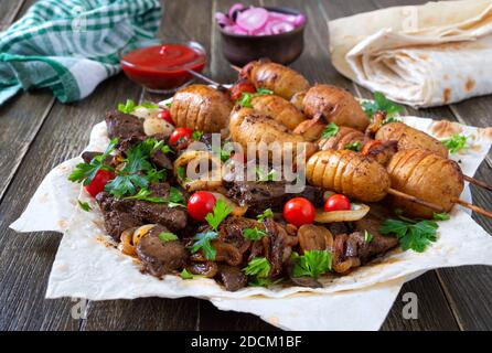 Gebratene Leber, Vollgemüse und Pilze auf Spieße mit Pita, Ketchup, eingelegten Gurken, roter Zwiebel. Speisekarte vom Grill-Restaurant. Georgische, asiatische Küche Stockfoto