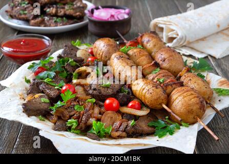 Gebratene Leber, Vollgemüse und Pilze auf Spieße mit Pita, Ketchup, eingelegten Gurken, roter Zwiebel. Speisekarte vom Grill-Restaurant. Georgische, asiatische Küche Stockfoto