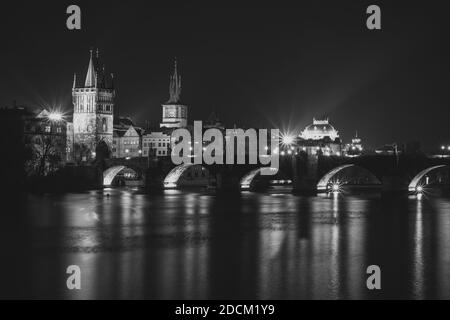 Abendpanorama von Prag, Tschechische Republik. Schwarzweiß-Foto. Karlsbrücke, Karluv spiegelt sich am meisten in der Moldau. Stadtlichter mit langer Belichtung Stockfoto