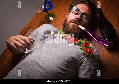 Junge mit einem Kater nach einer Silvesterparty auf dem Boden liegend. Stockfoto