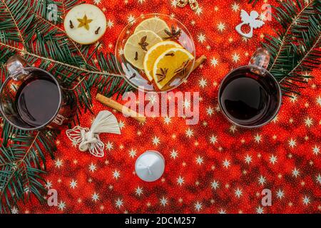 Zwei Tassen heißen Wein oder Gluhwein mit Zimt, Gewürzen und Orangenscheiben auf rotem Weihnachtshintergrund Draufsicht. Traditionelles Getränk im Winterurlaub.Mulled Stockfoto