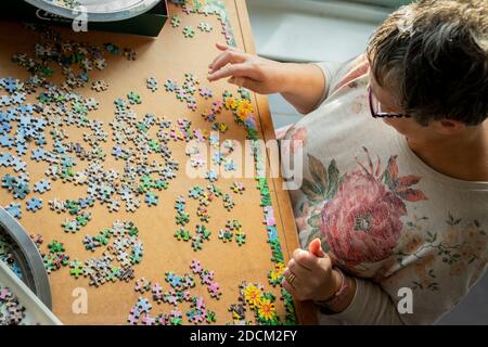 Frau mittleren Alters tut Puzzle zu Hause Stockfoto