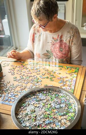 Frau mittleren Alters tut Puzzle zu Hause Stockfoto