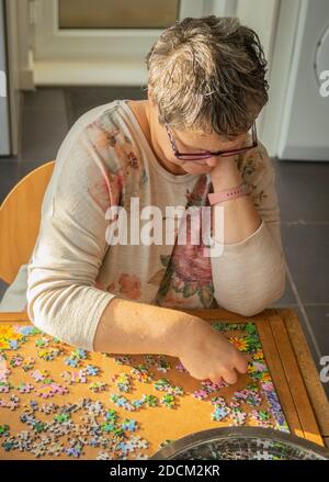 Frau mittleren Alters tut Puzzle zu Hause Stockfoto