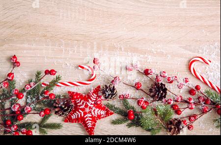 Flache Lay-Ansicht der Weihnachtsrahmen Hintergrund. Zweige mit roten Beeren, Filzsternornamenten, roten Zuckerstöcken und Fichtenzweigen, Kopierraum. Stockfoto