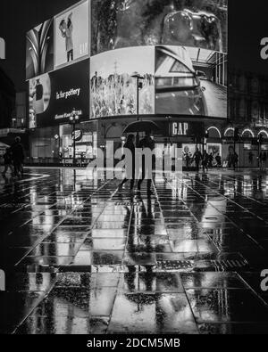 Der Rainy Piccadilly Circus spiegelt sich während der Absperrung in London unter den Lichtern der riesigen Werbetafel wider. Stockfoto