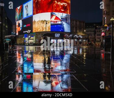 Der Rainy Piccadilly Circus spiegelt sich während der Absperrung in London unter den Lichtern der riesigen Werbetafel wider. Stockfoto