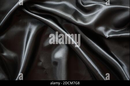 Falten schwarzen Satin Tuch Textur Hintergrund Stockfoto