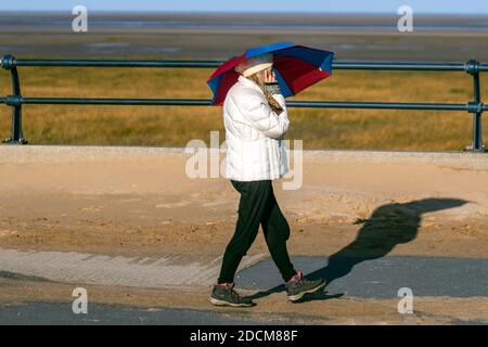 Regenschirm, um den Wind auf einem sonnigen in Southport, Merseyside UK Wetter zu schützen. 23. November 2020 Heller sonniger kalter Tag an der Küste, während die Anwohner die Wintersonne genießen. Kredit; MediaWorldImages/AlamyLiveNews Stockfoto