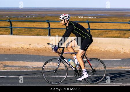 Männliche Radfahrer Reiten Sport Bianchi Rennrad in Southport, Merseyside UK Wetter. 23rd November, 2020 Heller sonniger kalter Tag an der Küste, da Einheimische die Wintersonne genießen. Stockfoto